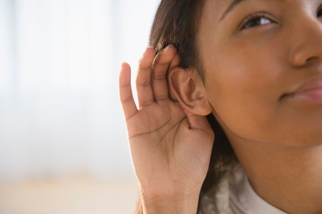 Woman holding her hand up to her ear